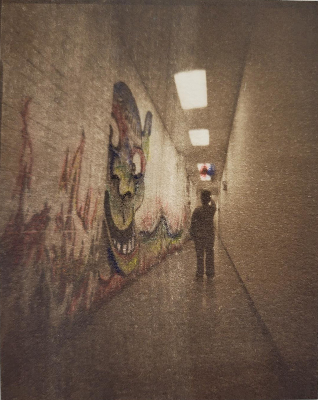 A hand tinted photograph of a hallway in some sort of institution building. A figure walks away from the camera in the center of the photo. On the left wall of the hallways is a graffiti piece that looks like a goblin creature has been tinted green, blue, and reds, and is surrounded by painted flames that stretch the length of the hall.